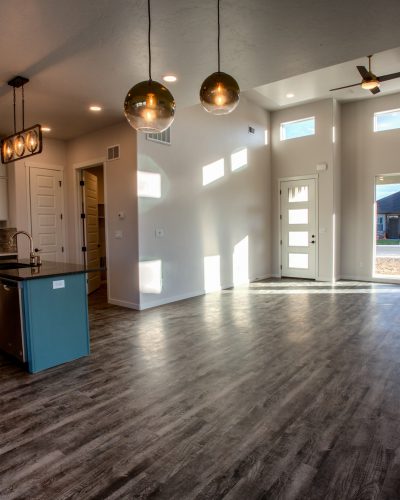 Wooden floors and high ceilings in a new home looking in toward the trendy kitchen.